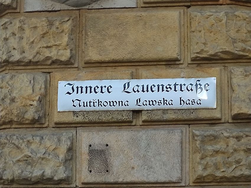 Zweisprachiges Straßenschild an einer Wand