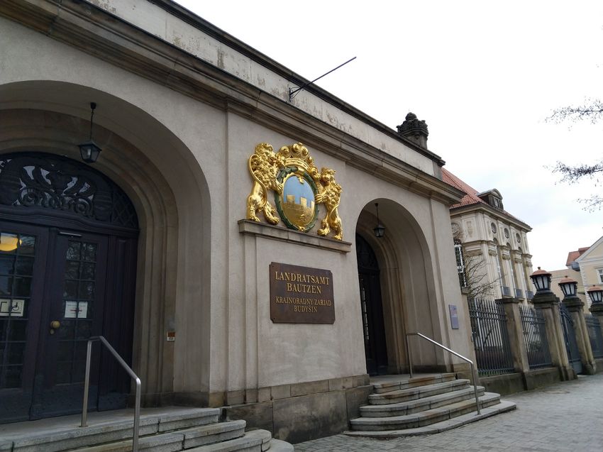 Außenansicht des Landratsamtes in Bautzen mit dem Namensschild, welche auch die sorbische Namensbezeichnung enthält