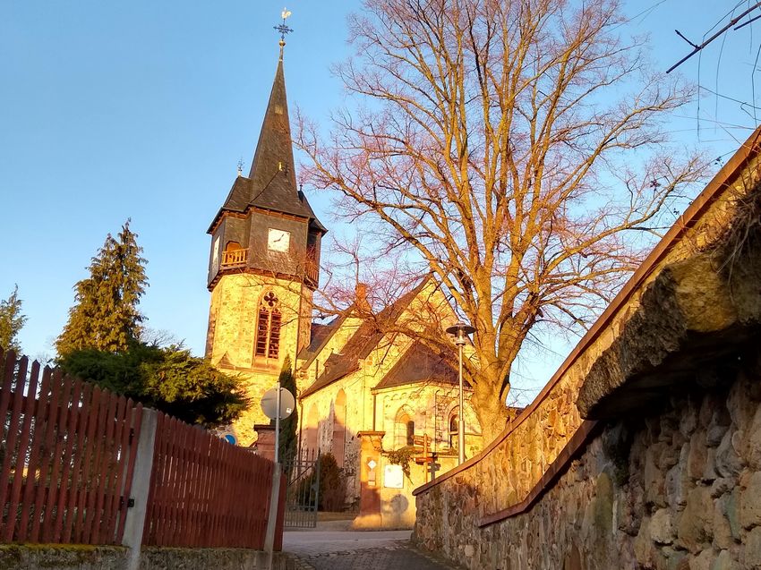 Eine von Sonne beschiene Kirche, im Vordergrund ein Weg